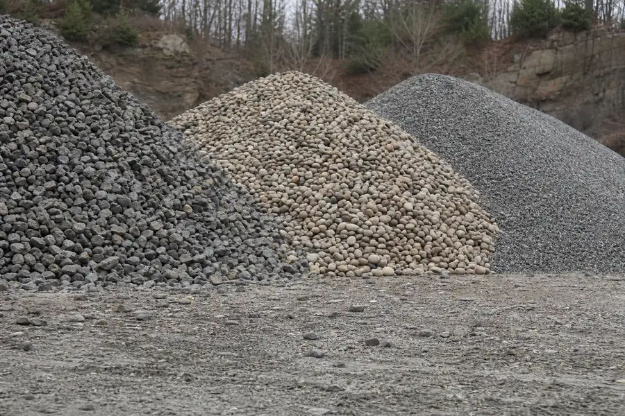 Side-by-side piles of trap rock, pea stone and processed gravel in a Connecticut stone yard
