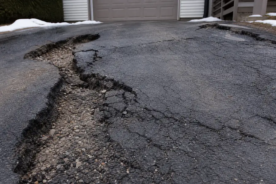 Cracked and heaved asphalt driveway surface caused by inadequate frost protection