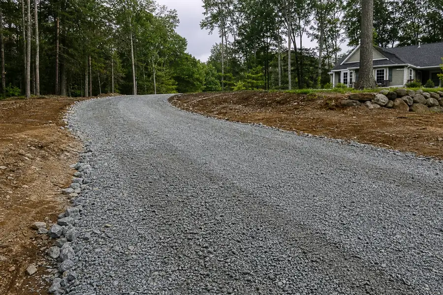 Newly graded gravel driveway base in Connecticut with compacted stone before paving