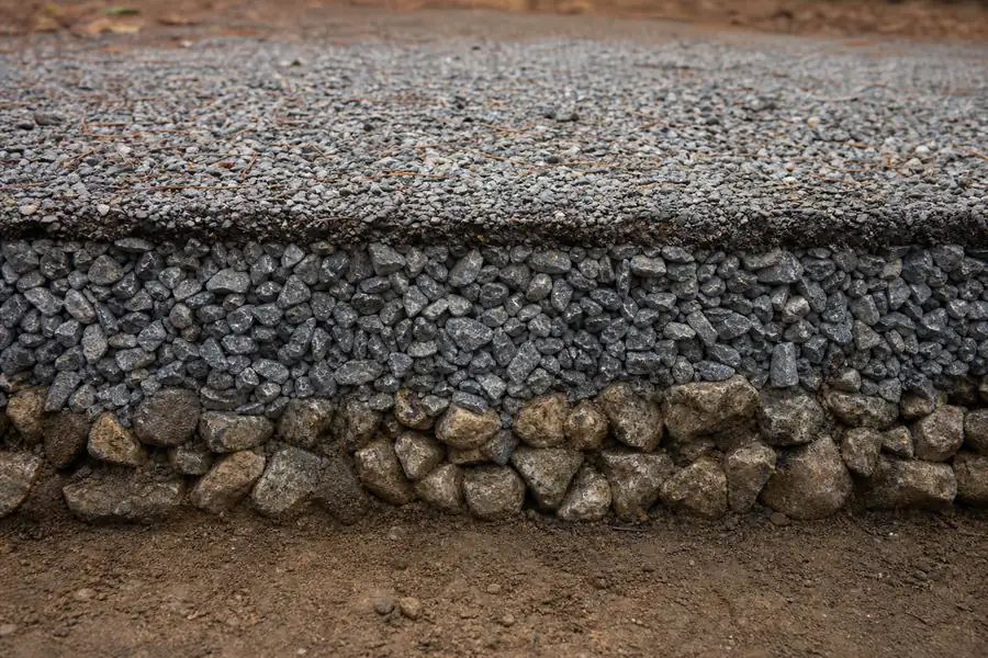 Cross-section cutaway of a gravel driveway showing three distinct stone layers