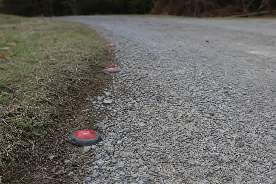 Driveway reflector markers being pushed into the edge of a gravel driveway